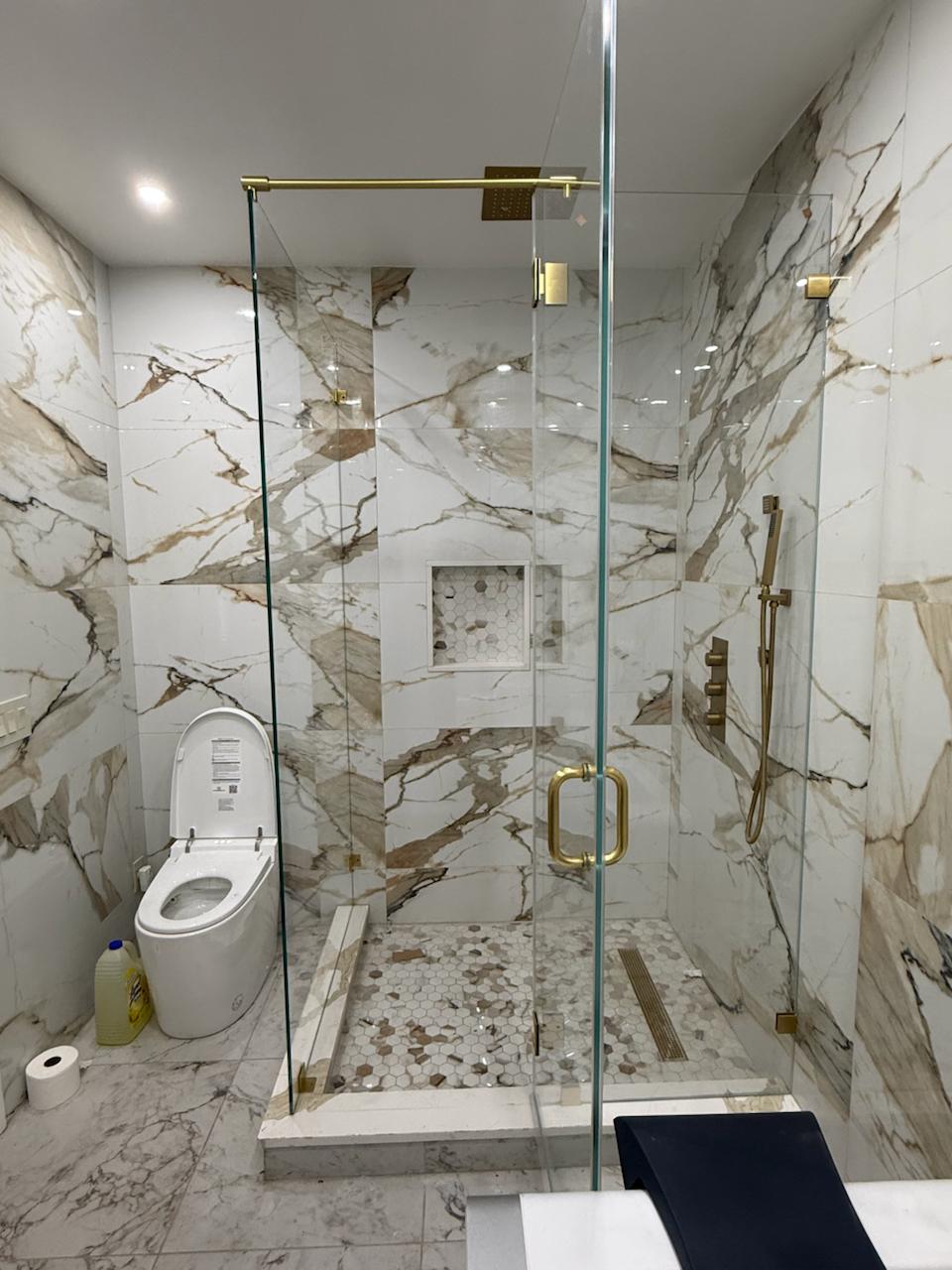 Crystal clear shower glass with gold hardware and support bar in Monsey